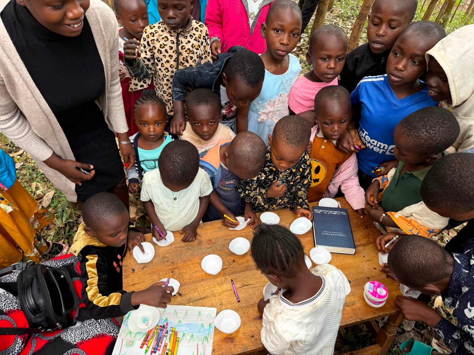 Children gathered around a table with a Bible and a drawing activity