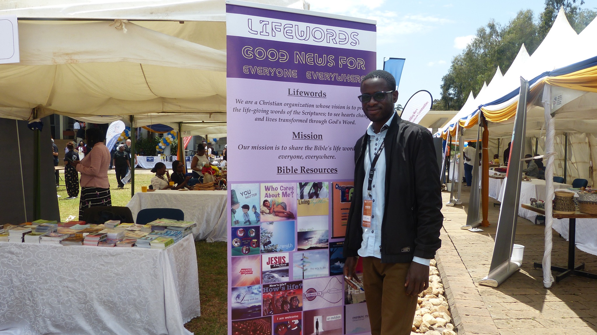 A Lifewords representative beside a display of Bible-based ministry resources in Kenya
